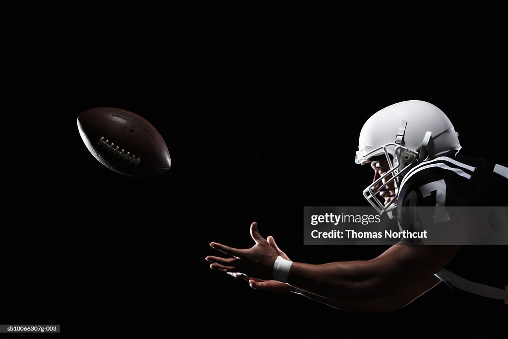American football player catching ball, side view
