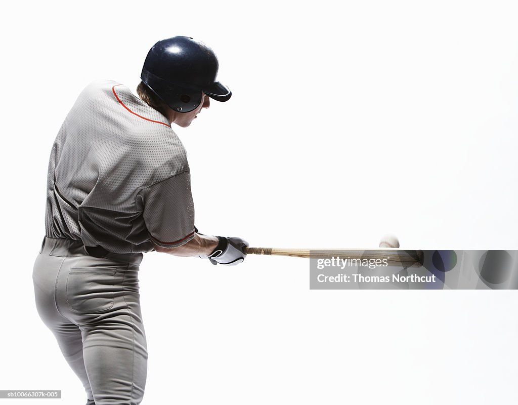 Baseball player swinging bat, rear view