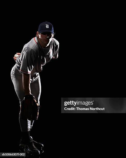 baseball pitcher bending down, holding ball behind back, portrait - baseball pitcher stock pictures, royalty-free photos & images