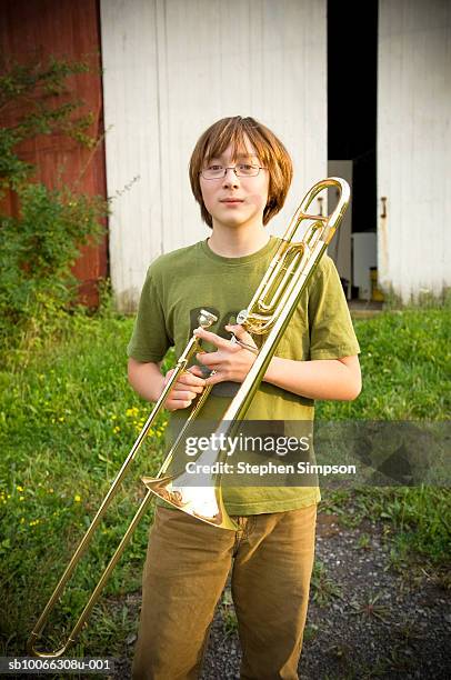 teenage boy (14-15) holding trombone at barn - trombone stock pictures, royalty-free photos & images