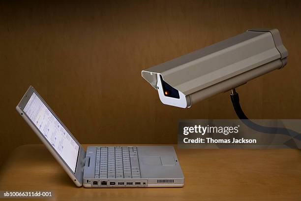 surveillance camera peering into laptop computer - tracking fotografías e imágenes de stock