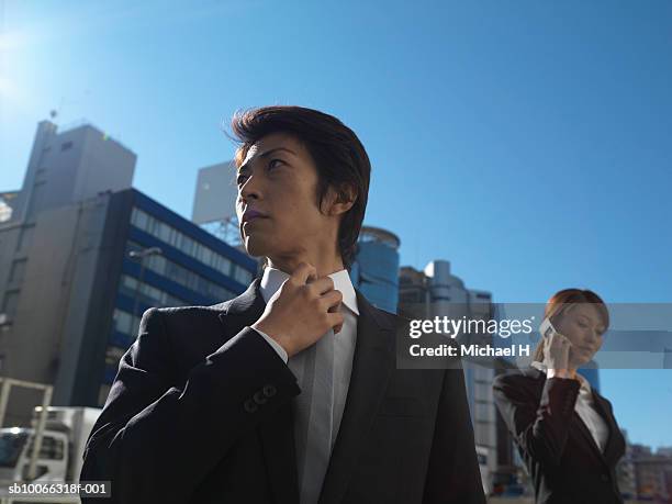 businessman and woman in front of office buildings - adjusting blue tie stock-fotos und bilder