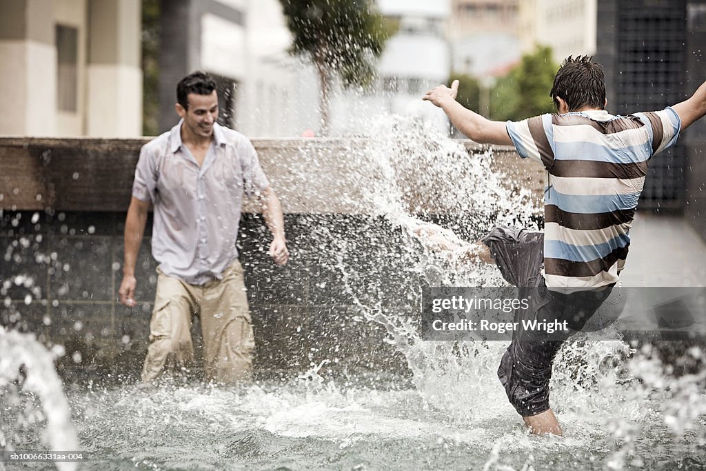 Two men splashing in fountain