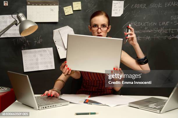 young woman using three laptops with four hands, smiling, portrait - versatile foto e immagini stock