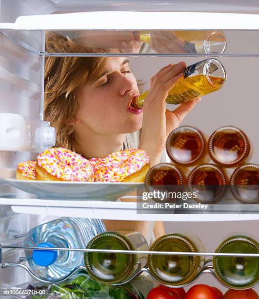 young man drinking alcohol from fridge - beverage fridge stock pictures, royalty-free photos & images