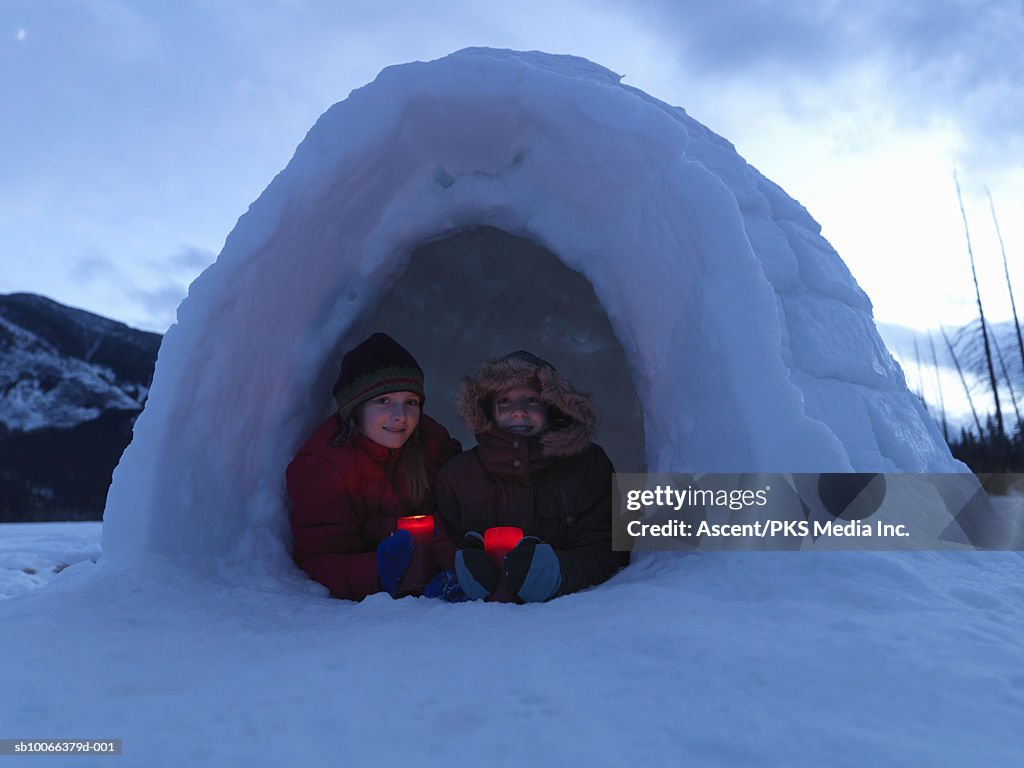 Girls (8-13) holding candles in igloo, smiling, portrait