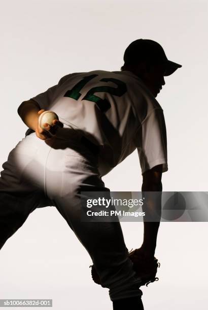 silhouette of baseball pitcher holding ball behind back, rear view, close-up - baseball stock pictures, royalty-free photos & images