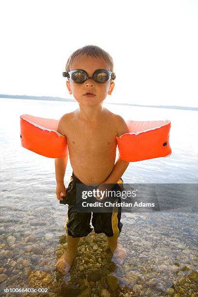 boy (2-3) with swimming goggles and armband in sea - brazaletes acuáticos fotografías e imágenes de stock