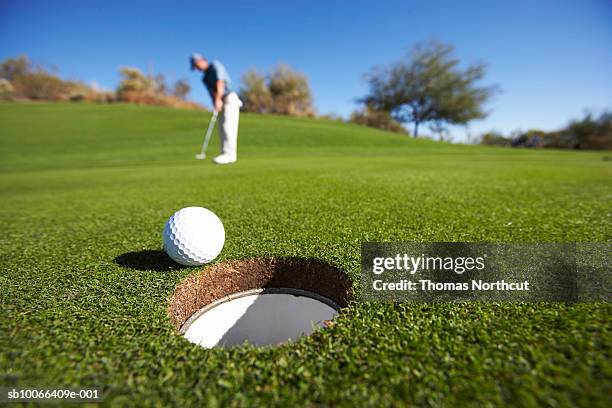 male golfer putting on golf course - agujero fotografías e imágenes de stock