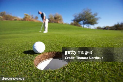 Male golfer putting on golf course Male golfer putting on golf course