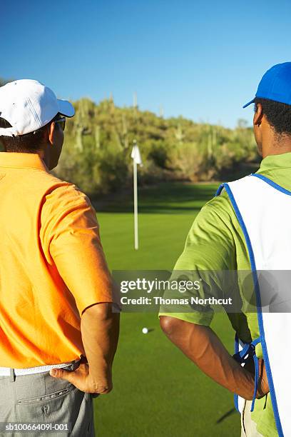 golfers standing on putting green at golf course - golf caddy stock-fotos und bilder