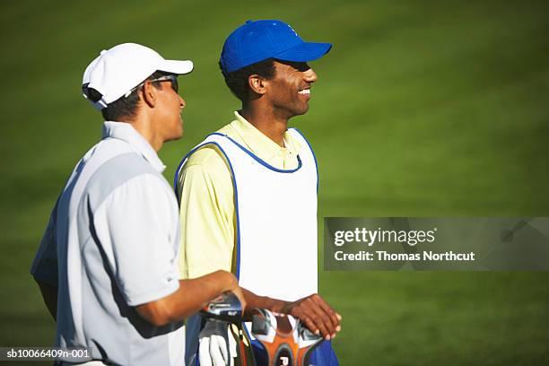 golfers standing on golf course, smiling - golf caddy stockfoto's en -beelden