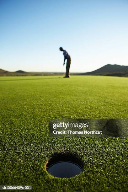 male golfer putting on golf course - green de golf photos et images de collection
