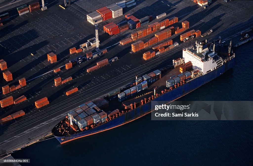 Cargo at quay loading freight container at port, aerial view