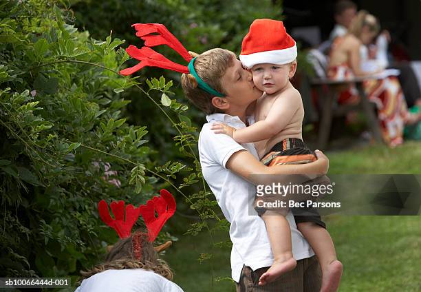 jungen (12-13) küssen bruder (16 bis 18 monate) auf der rasenfläche mit christm - christmas australia stock-fotos und bilder
