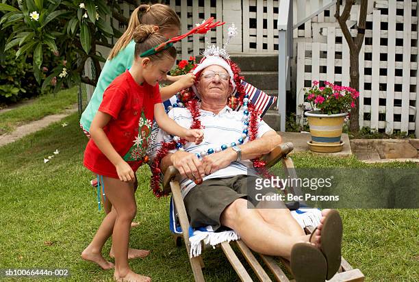 children (7-9) decorating senior man with christmas decorations in yard - last christmas stock pictures, royalty-free photos & images