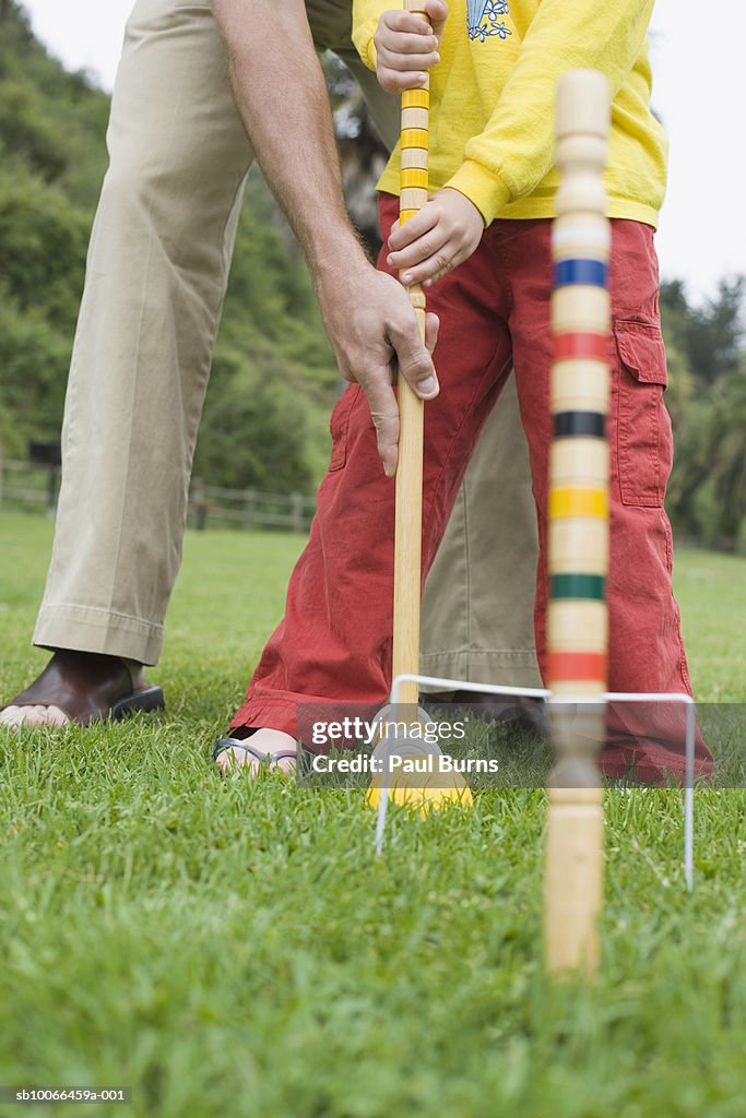 Low section view of man with son (8-9) playing croquet