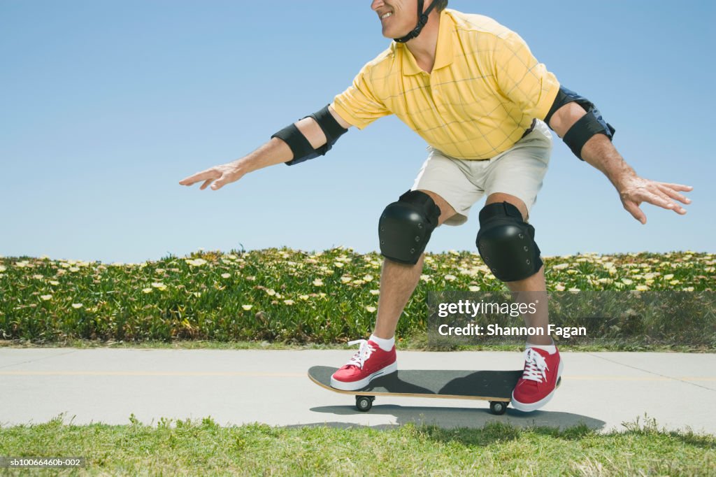 Man skateboarding on footpath in garden, low section