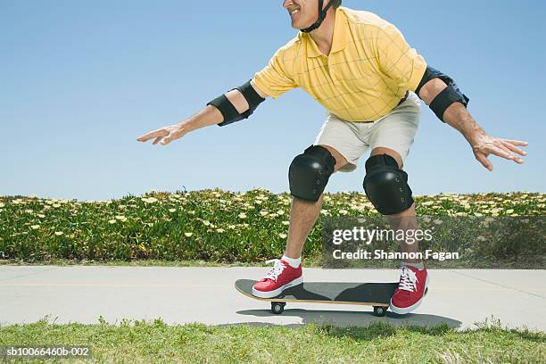 man skateboarding on footpath in garden, low section - kneepad stock pictures, royalty-free photos & images