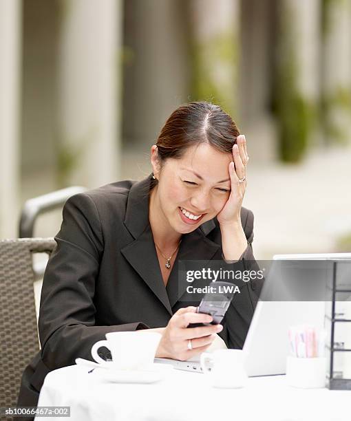 businesswoman using laptop and mobile phone at pavement caft, smiling - caft stock pictures, royalty-free photos & images
