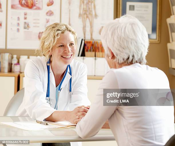 female doctor assisting senior woman, smiling - patientin stock-fotos und bilder