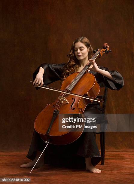 young woman sitting on playing cello - música clásica fotografías e imágenes de stock