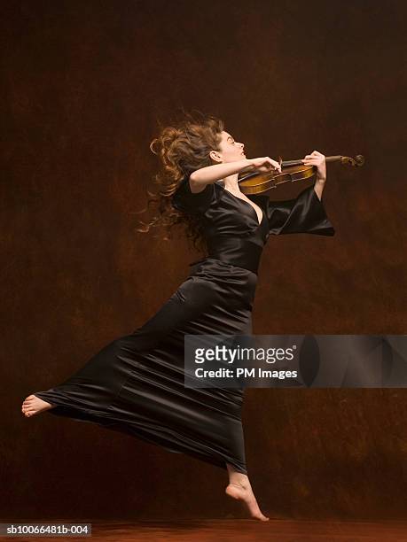 young woman playing violin and jumping, side view - violinist stock pictures, royalty-free photos & images