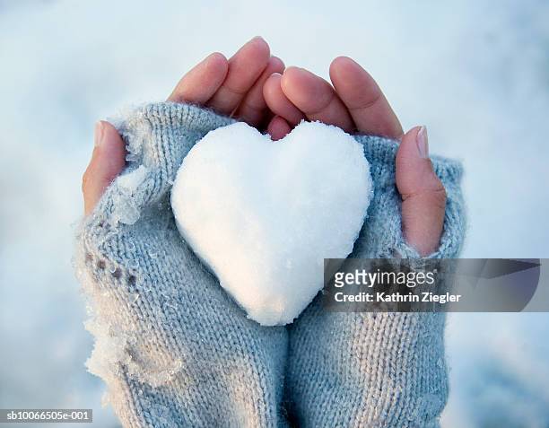 woman holding heart-shaped snowball, close-up of hands - bola de neve imagens e fotografias de stock