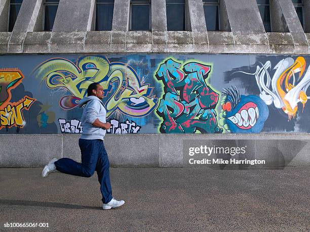 young man jogging past graffiti wall - street art stock pictures, royalty-free photos & images