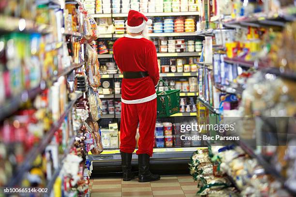 man dressed as santa claus standing in supermarket, rear view - father christmas hat stock pictures, royalty-free photos & images