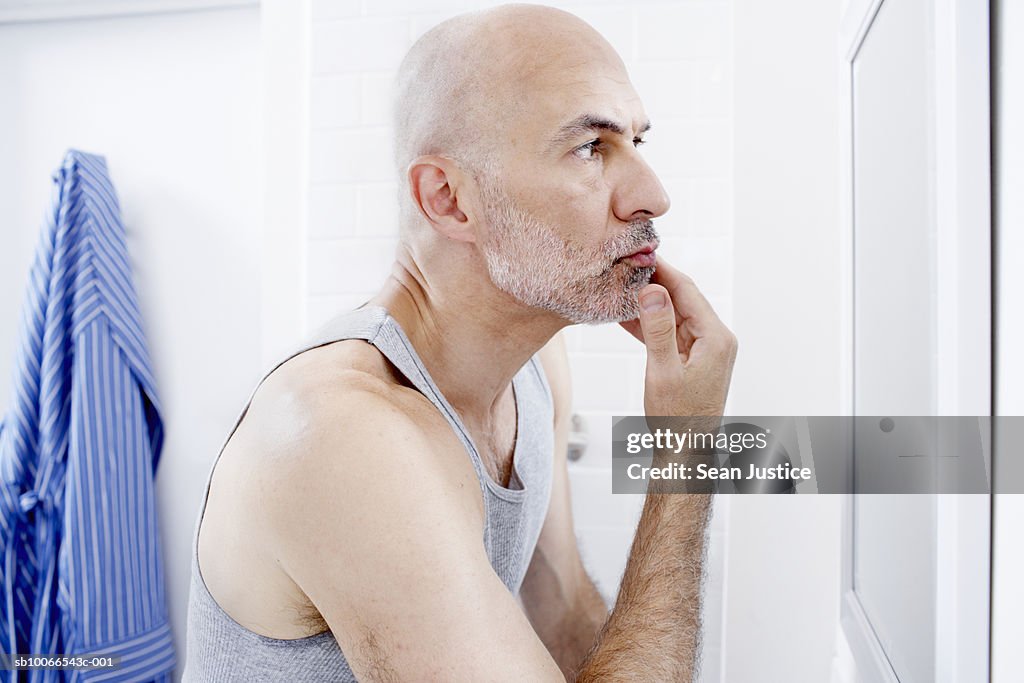 Man examining face in mirror