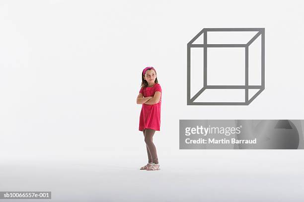 girl (8-9) looking at geometric outline of box on white background - kids standing crossed arms stock-fotos und bilder