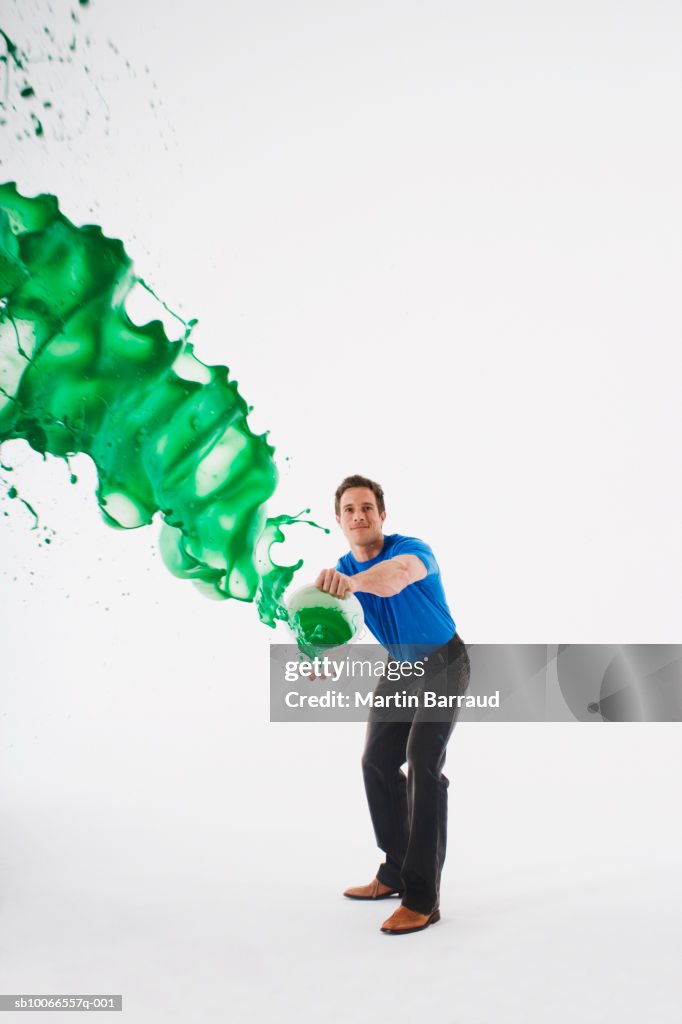 Man throwing tin of green paint, studio shot