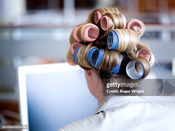 businesswoman with hair on curlers in office, rear view - hair rollers stock pictures, royalty-free photos & images