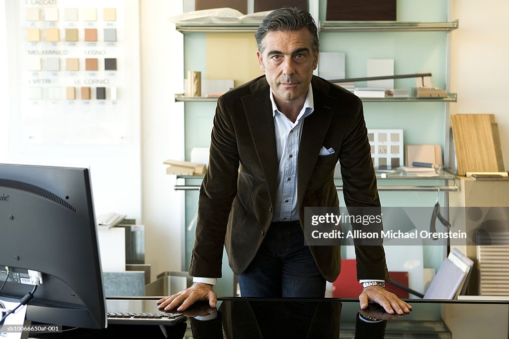 Man standing at desk in office, portrait