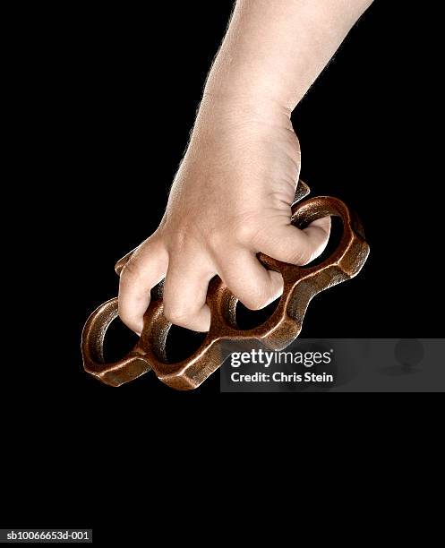 hand holding brass knuckles on black background - knuckle duster imagens e fotografias de stock