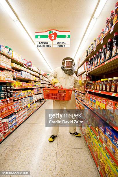 man in bee keeper suit shopping in supermarket - protection humour stock-fotos und bilder