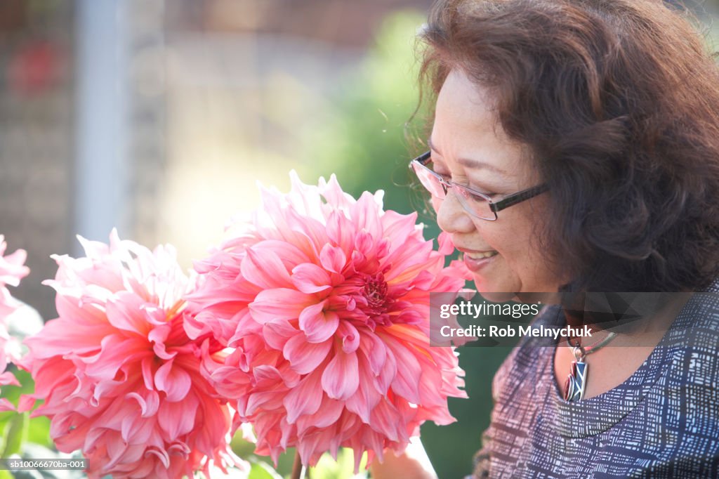 Senior woman smelling flowers, outdoors, close-up