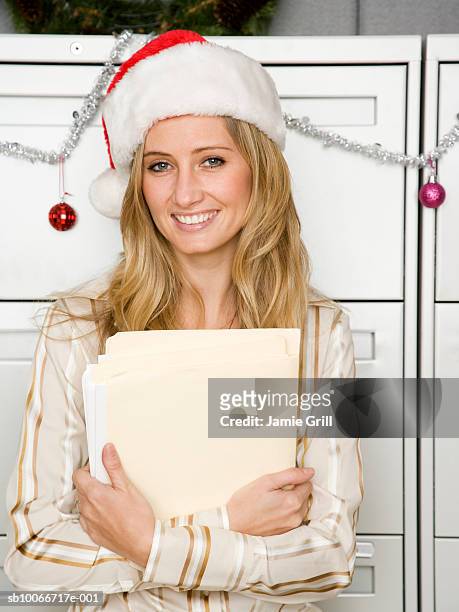 young woman in office wearing santa hat, smiling, portrait - christmas party office stock-fotos und bilder