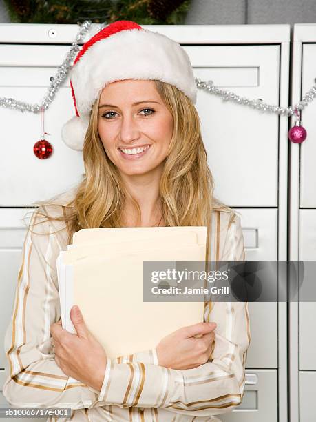 young woman in office wearing santa hat, smiling, portrait - christmas office party stock pictures, royalty-free photos & images