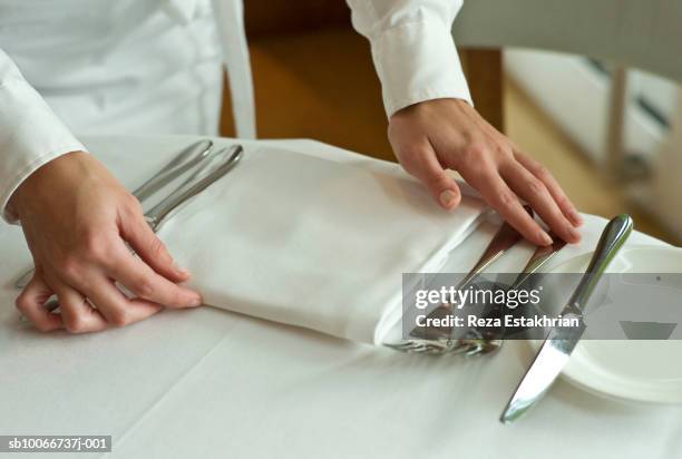 waitress adjusting table settings in restaurant, mid section - servilleta fotografías e imágenes de stock