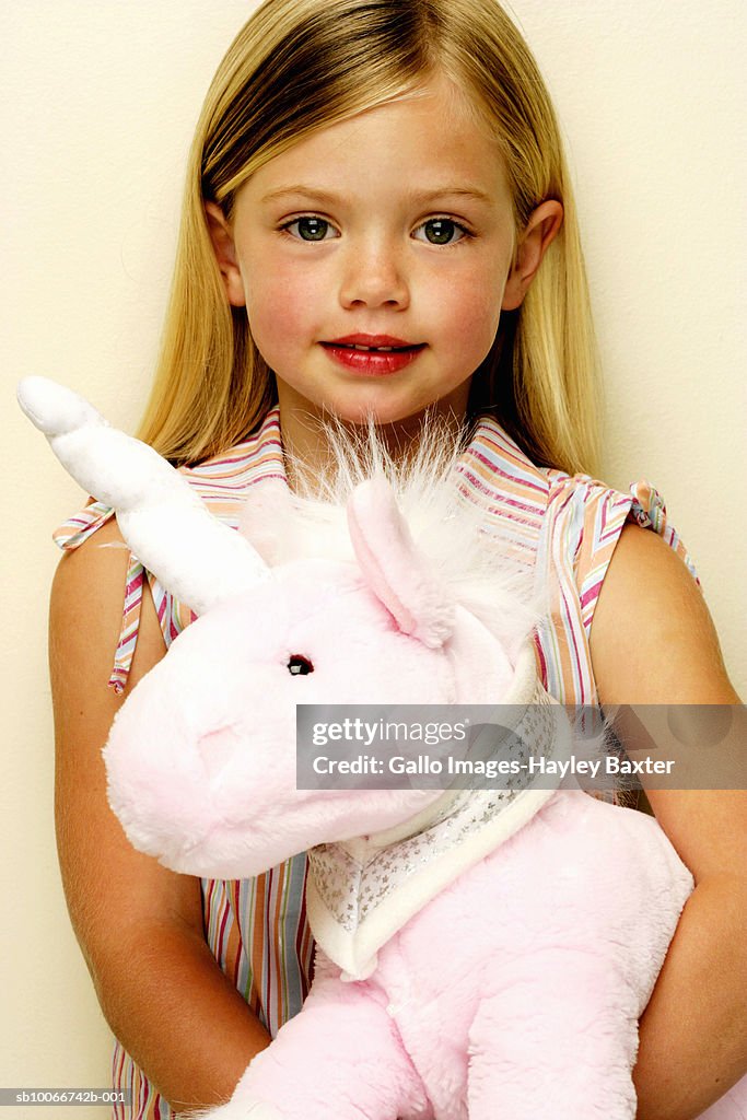 Portrait of young girl (4-5) with stuffed unicorn