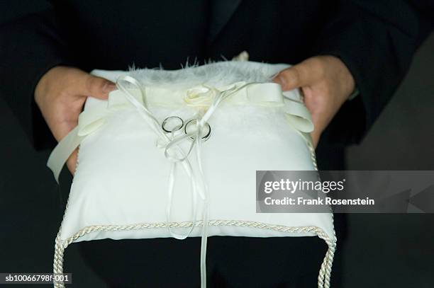man holding pillow with rings on it, mid section - pageboy stock-fotos und bilder