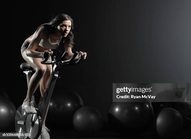 young woman using exercise bike in gym - spinning bikes stock pictures, royalty-free photos & images