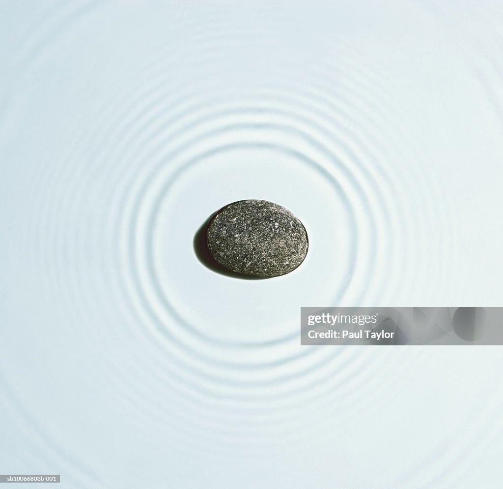 Stone causing ripples on water, close-up