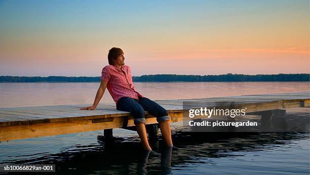 man sitting on jetty with feet in water - ankle deep in water stock pictures, royalty-free photos & images