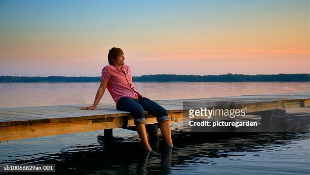 man sitting on jetty with feet in water - ankle deep in water bildbanksfoton och bilder