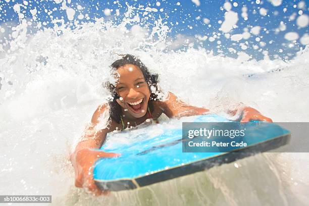 young woman bodyboarding on beach, laughing - bodyboard stock pictures, royalty-free photos & images