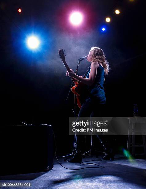 woman playing guitar and singing on stage - best rock performance stock pictures, royalty-free photos & images