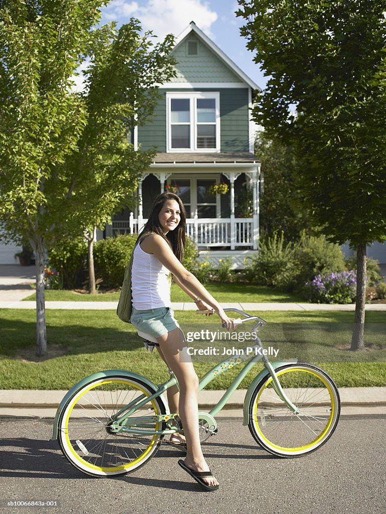 Teenage girl (14-15 years) riding cruiser bike on suburban street